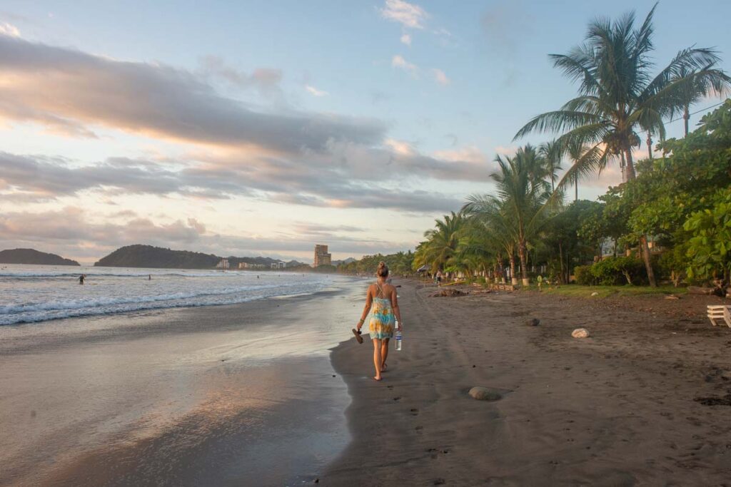 A lady walks along Jaco Beach at sunset